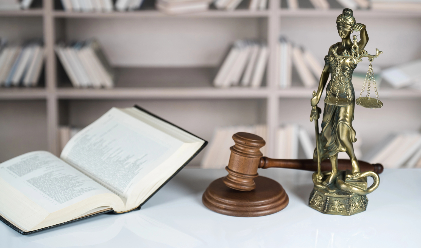Wooden gavel and sculpture of blind Themis holding empty balance scales, mythological Greek goddess, symbol of justice
